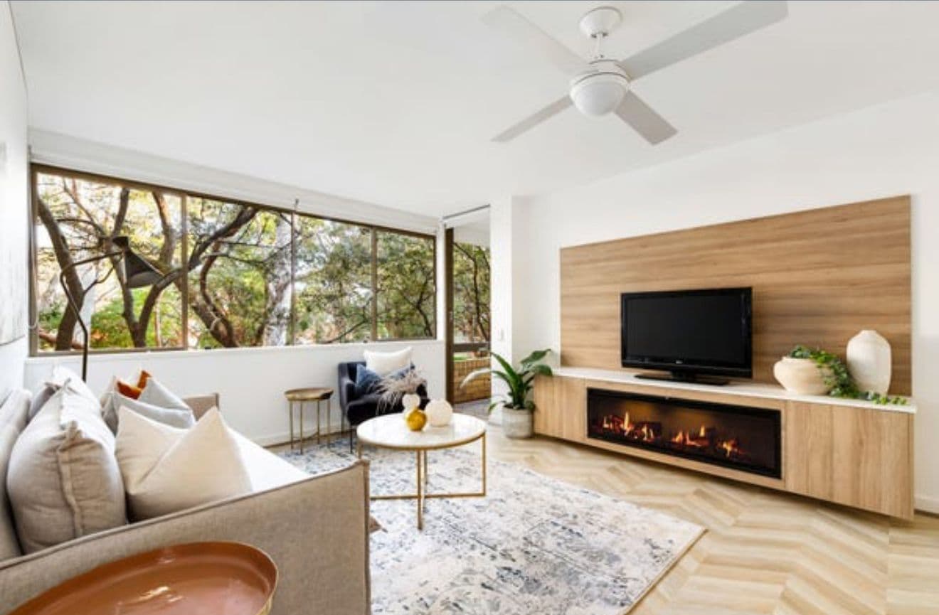 Renovated living room with a feature timber wall and built-in fireplace by Reno Build on Sydney's Northern Beaches