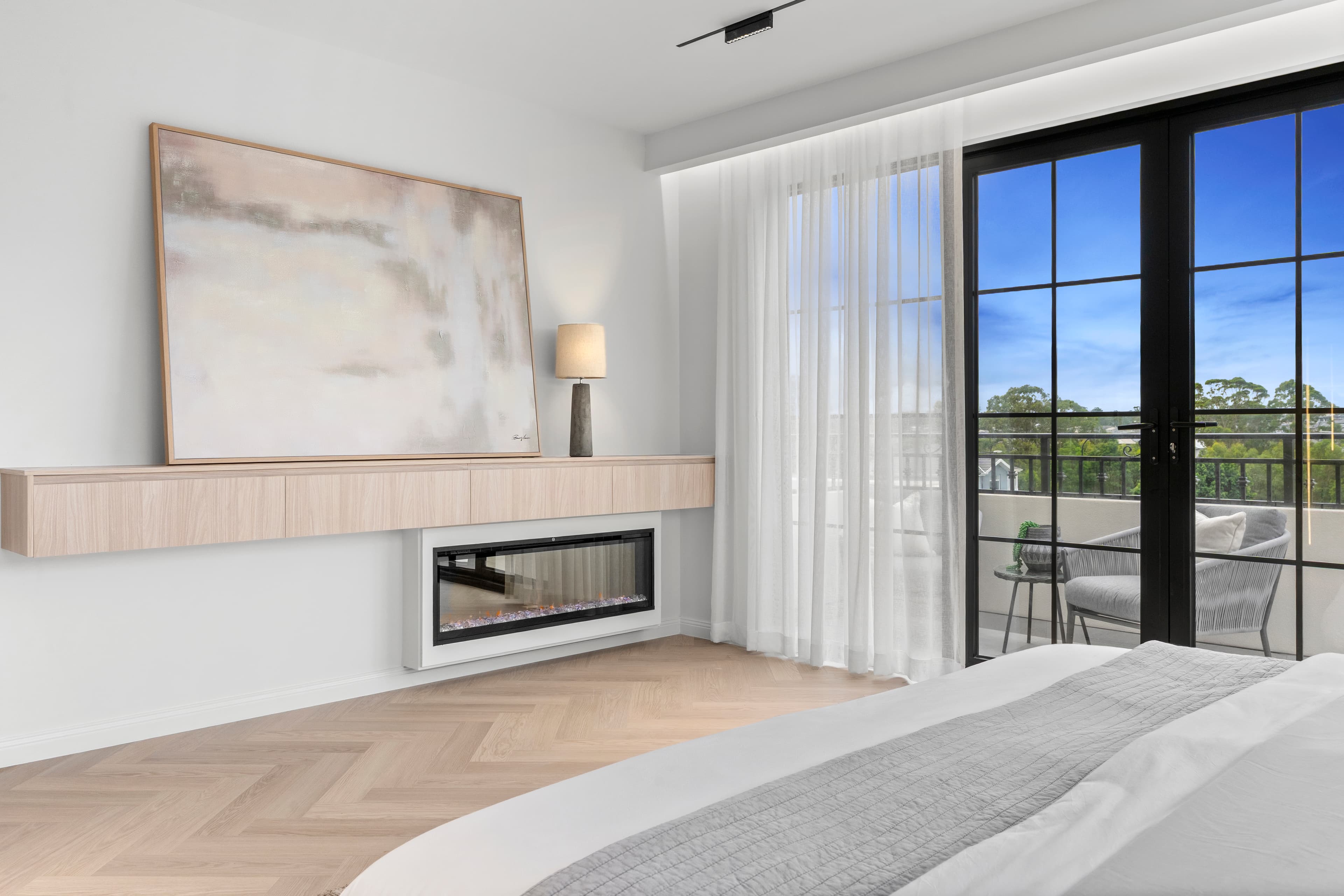 Renovated master bedroom with herringbone timber floors, a linear gas fireplace and built-in joinery by Reno Build on Sydney's Northern Beaches