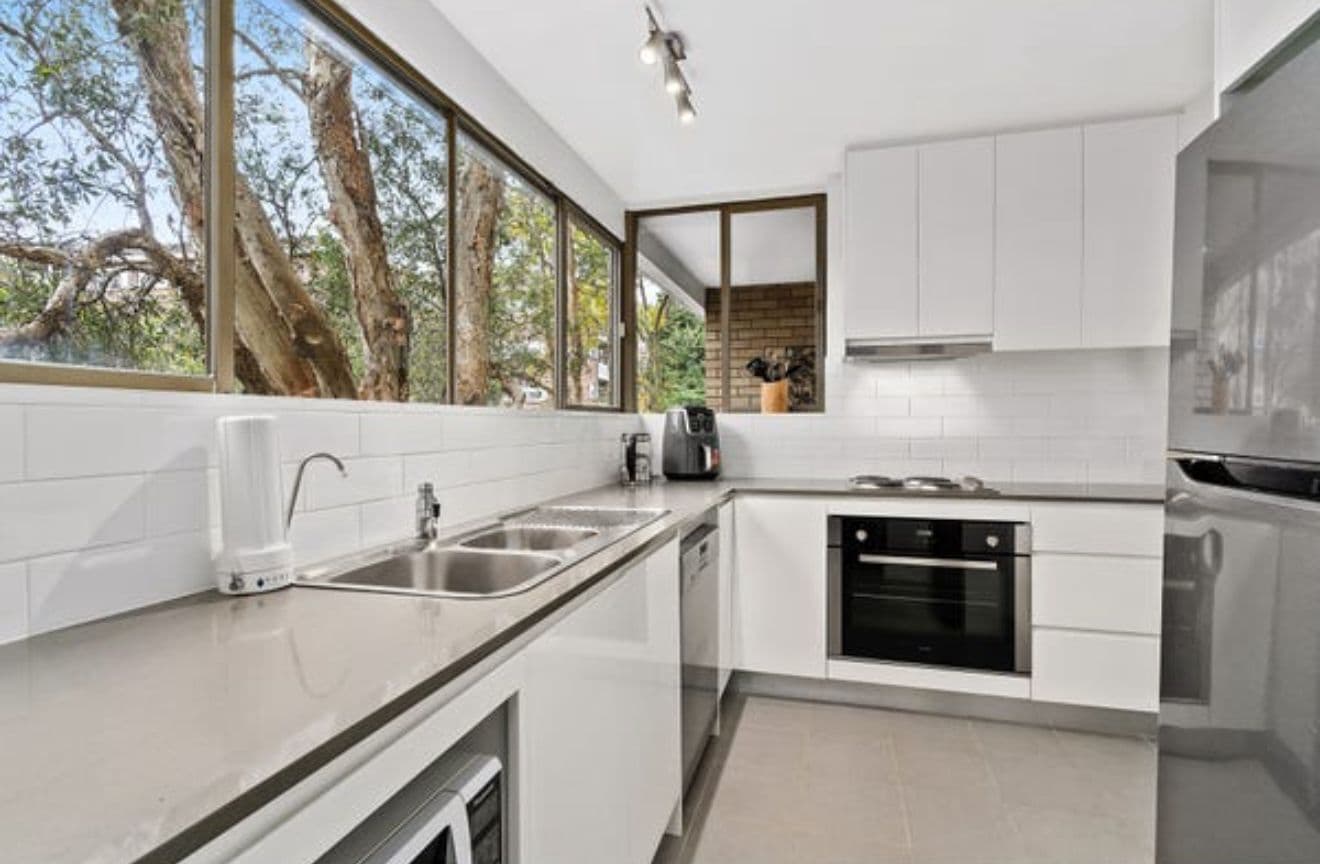 Budget-smart galley kitchen with white subway tiles and a stone-grey benchtop by Reno Build in Sydney